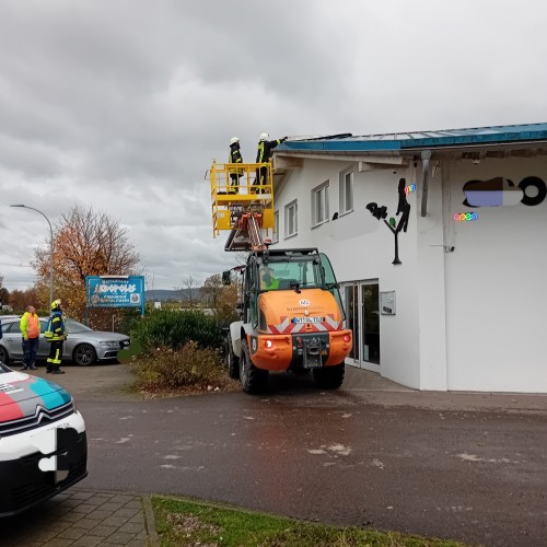 Zwei Einsatzkräfte in einem von dem Bagger hochgehobenen Korb