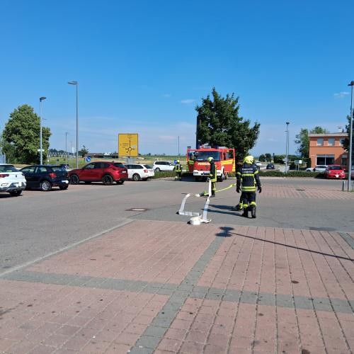 Zwei Feuerwehrmänner rollen Schläuche aus